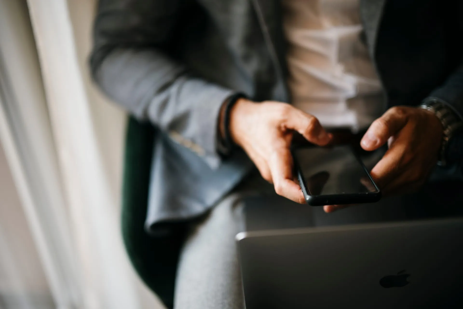 Persona usando una aplicación móvil en su teléfono junto a un notebook